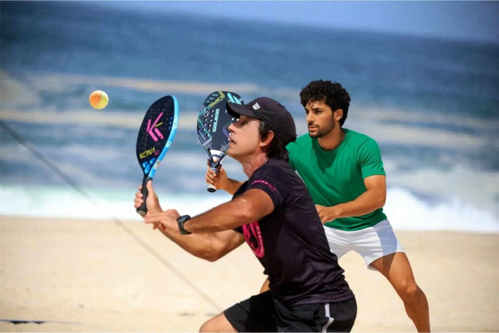Dupla de atletas fazendo uma defesa alta num jogo no CT Performance Beach Tennis em Itaipuaçu.