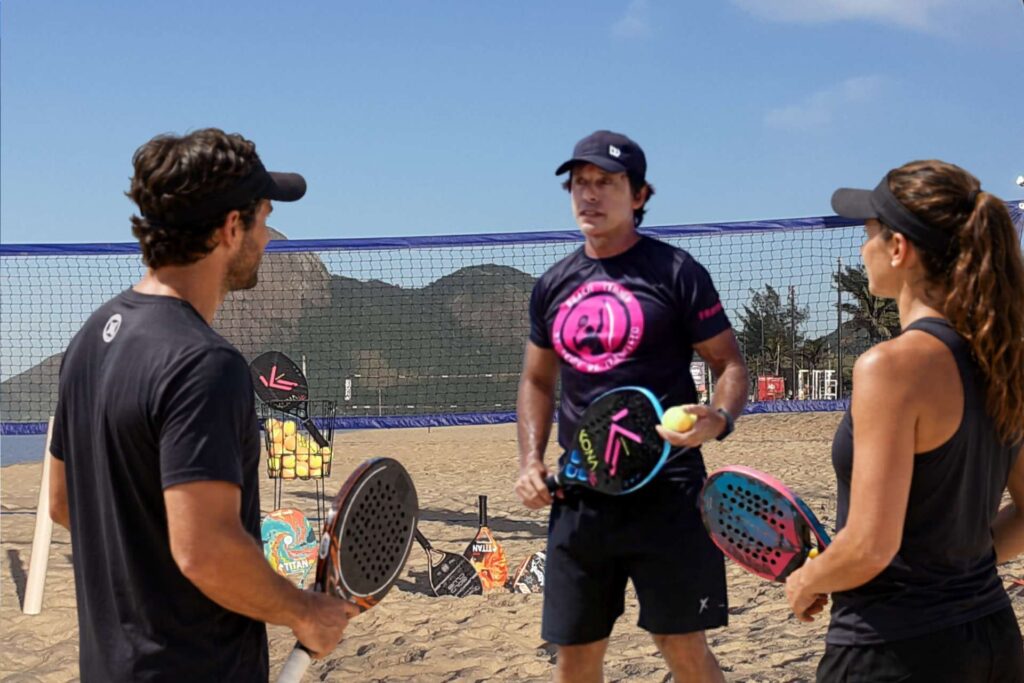 Professor Mauro conversando com casal de alunos durante uma aula de beach tennis em Itaipuaçu.